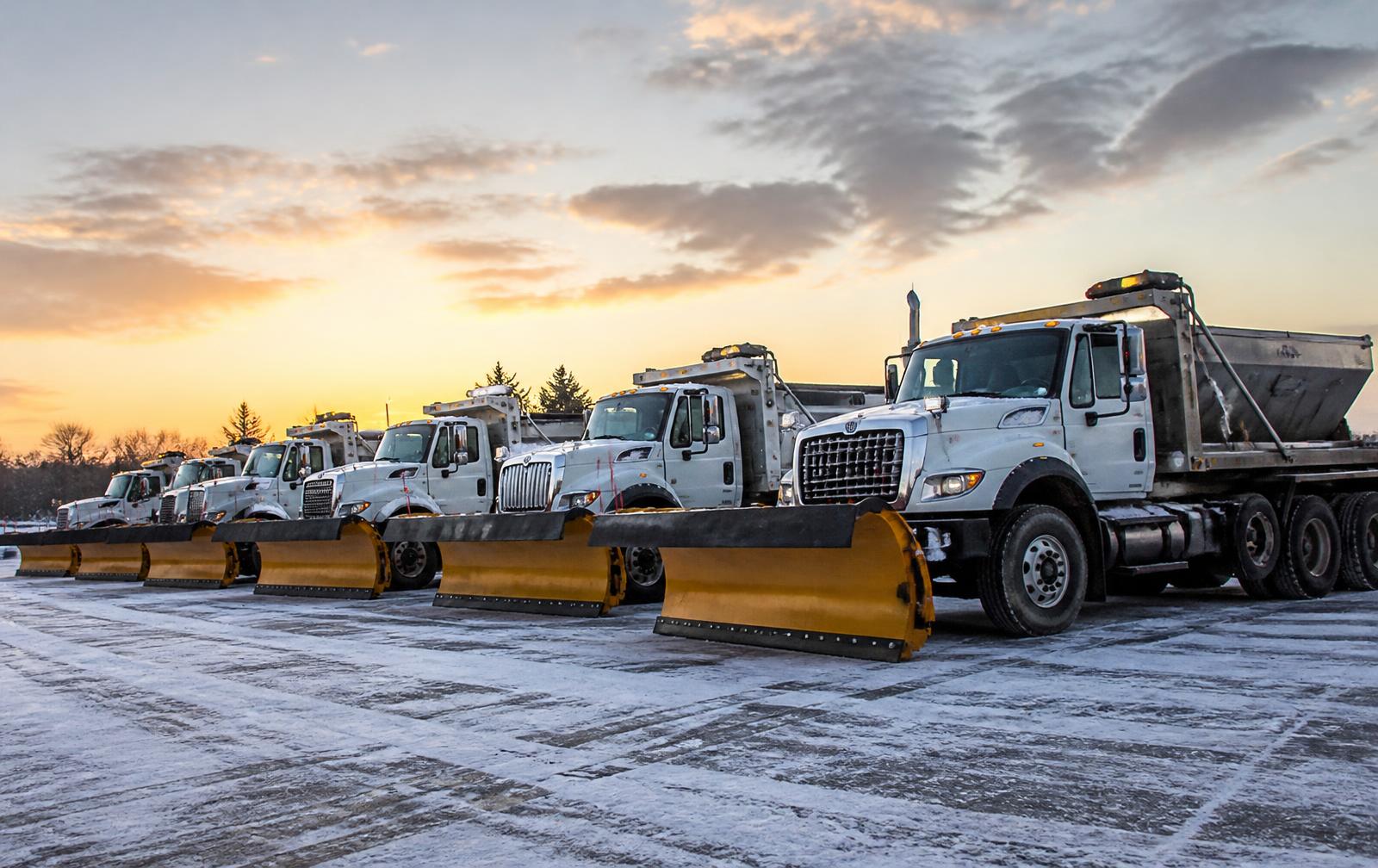 Fleet of Snow Authority plow trucks and salt spreaders staged and ready at dawn